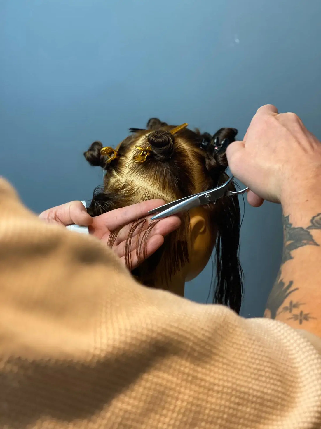 Person getting their hair styled with akito scissors against a blue background
