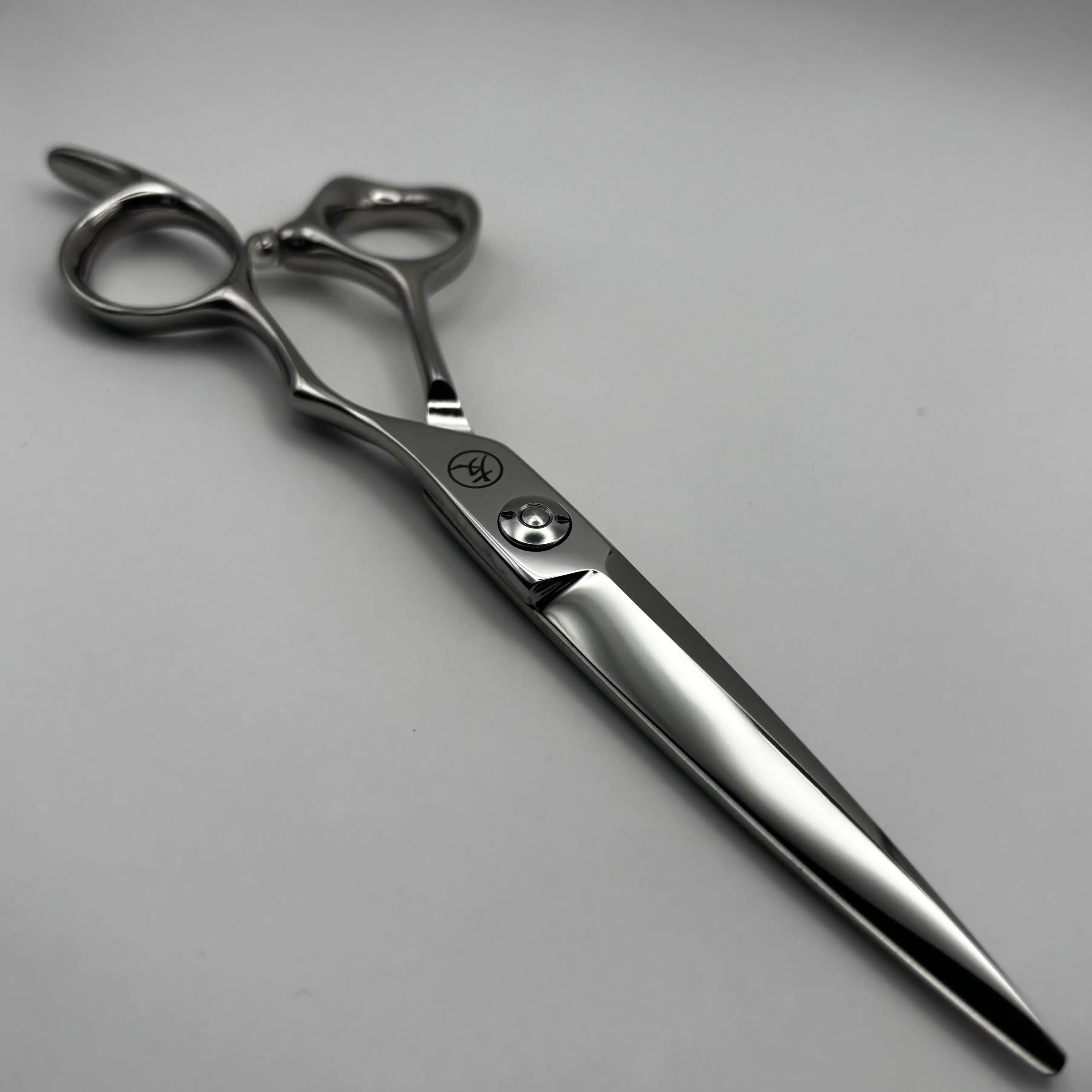 A pair of polished K-5 steel professional hair shears with ergonomic double-loop handles, shown on a neutral light grey background.
