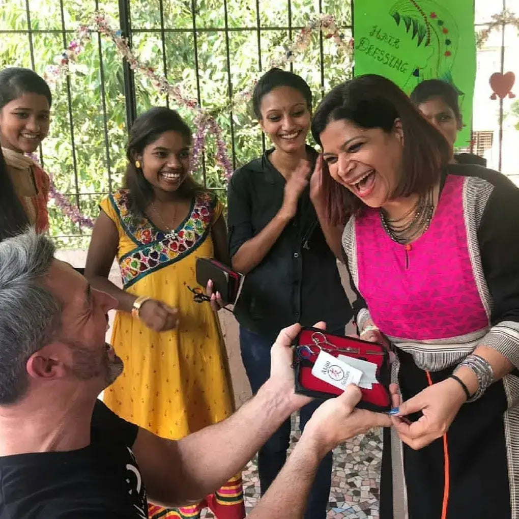 Woman receiving a small gift from a man with people watching in a casual outdoor setting.