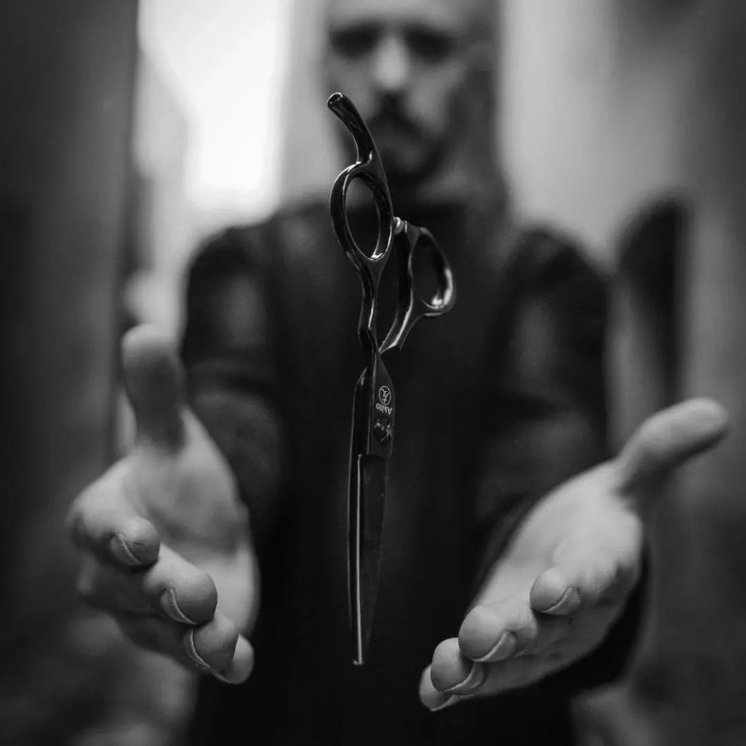 Person holding a pair of akito scissors between their palms with a blurred background