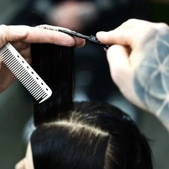 Person cutting hair with scissors and a comb in a close-up shot