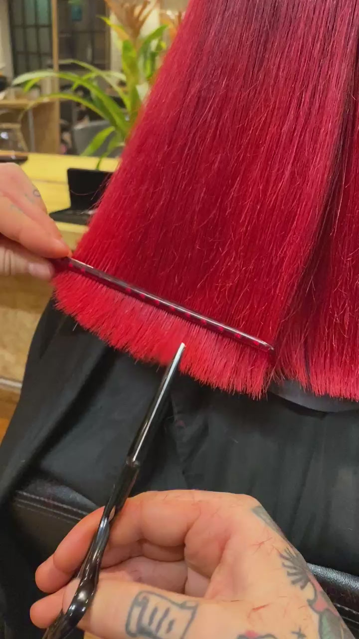 Hairdresser point cutting a customers red hair using black Akito F-2
