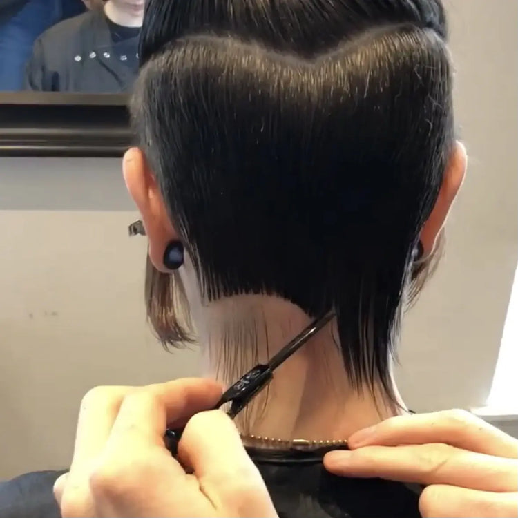 Person getting a haircut with a hairdresser using scissors and a comb.